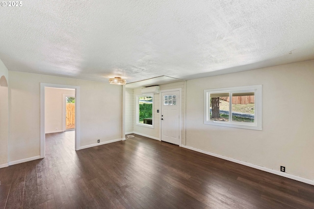 1565 California Ave, Coos Bay, OR 97420 - unfurnished living room with a wall mounted AC, a textured ceiling, dark wood-style floors, and arched walkways