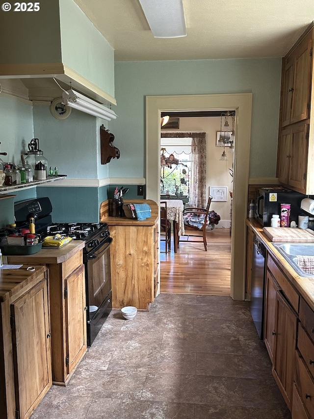 45 S 12th St, Cottage Grove, OR 97424 - kitchen with black range with gas stovetop, exhaust hood, dishwashing machine, a sink, and light countertops