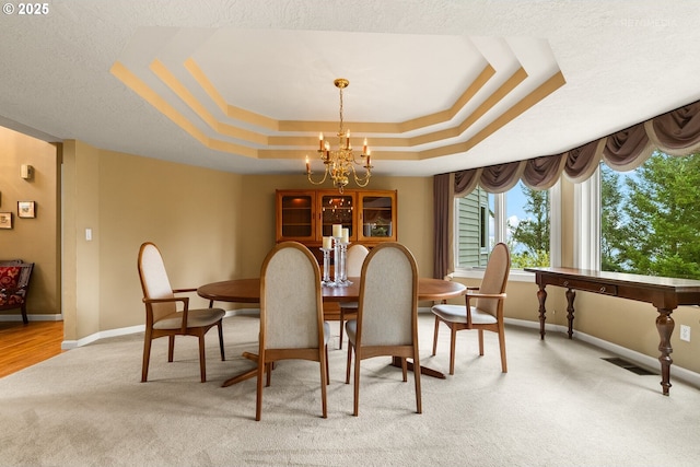 dining room with a chandelier, baseboards, light colored carpet, and a raised ceiling