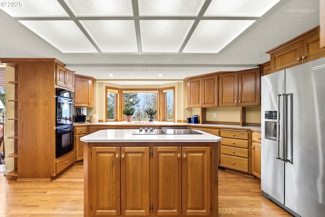 kitchen with light countertops, light wood-style floors, a center island, and black appliances
