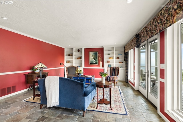 living room featuring visible vents, built in shelves, baseboards, a textured ceiling, and stone tile floors