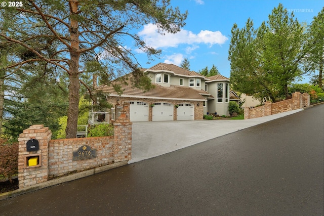 view of front facade with concrete driveway, fence, and a garage