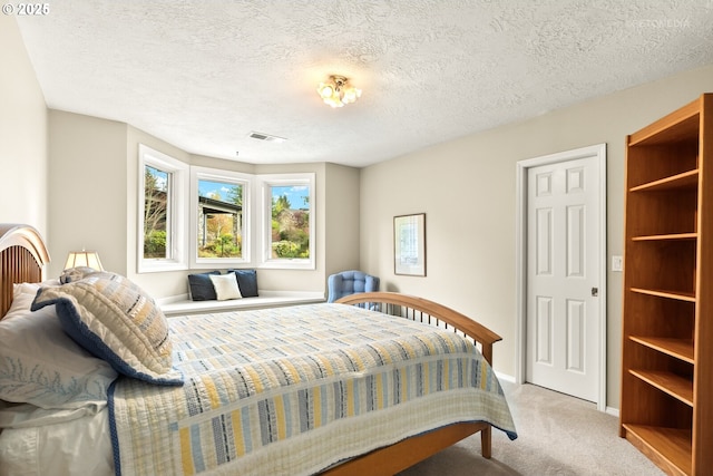 bedroom featuring carpet flooring, visible vents, baseboards, and a textured ceiling