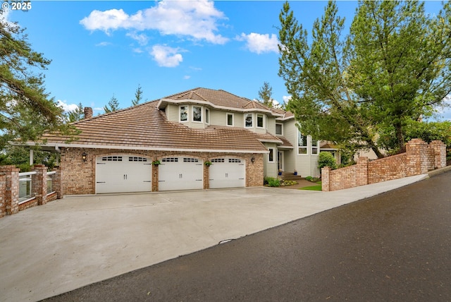 view of front of home featuring a chimney, fence, a garage, and concrete driveway