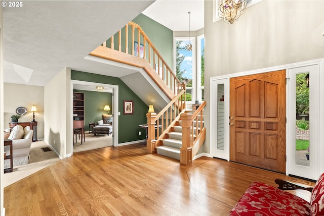 foyer entrance featuring a wealth of natural light, stairway, a high ceiling, and wood finished floors