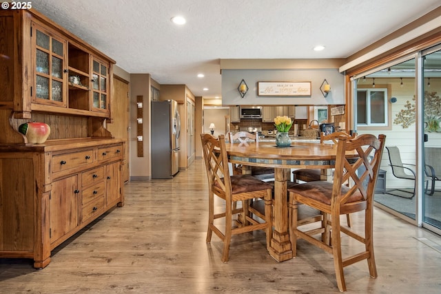 dining room with light hardwood / wood-style flooring and a textured ceiling