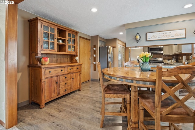 dining area featuring light hardwood / wood-style flooring and a textured ceiling