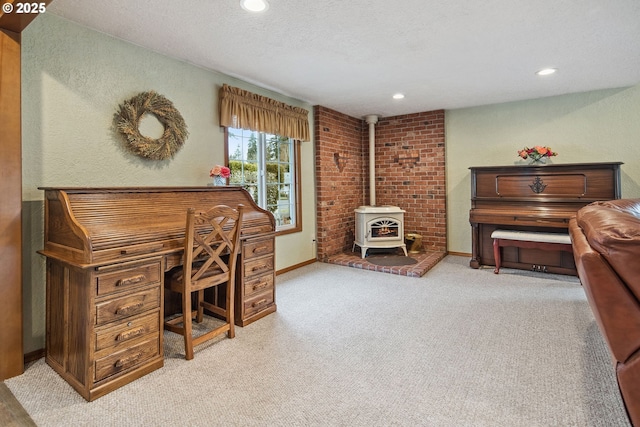 home office with light carpet, a textured ceiling, and a wood stove