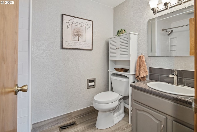 bathroom with wood-type flooring, toilet, vanity, and a shower