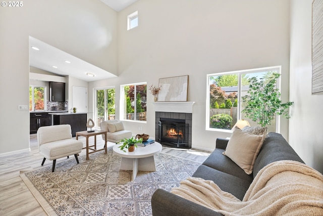 17848 SW Eldred Ln, Sherwood, OR 97140 - living room with a high ceiling, light wood-style floors, a tile fireplace, recessed lighting, and baseboards