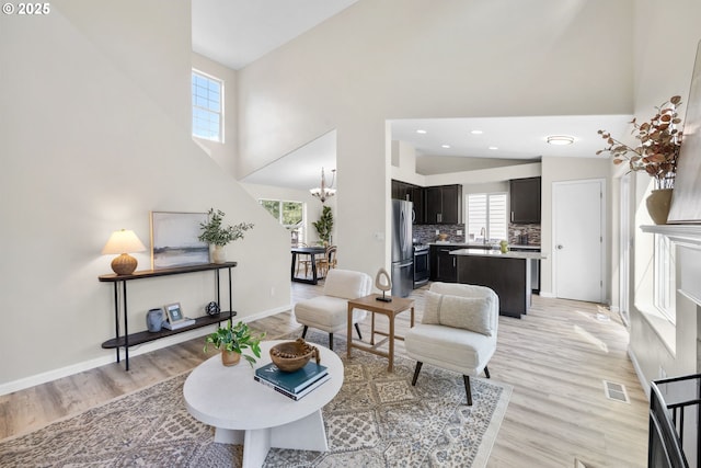 17848 SW Eldred Ln, Sherwood, OR 97140 - living area with light wood-style floors, a towering ceiling, baseboards, a chandelier, and recessed lighting