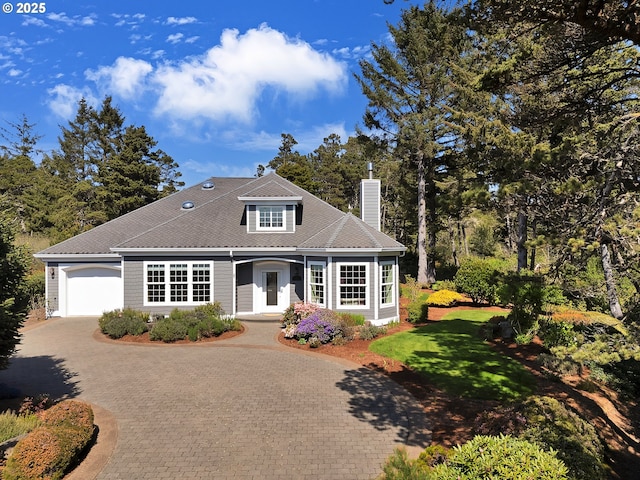 view of front facade with a garage, decorative driveway, a front yard, and a chimney