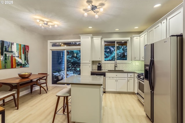 9480 SW 153rd Ave, Beaverton, OR 97007 - kitchen with appliances with stainless steel finishes, light wood-style floors, decorative backsplash, white cabinets, and recessed lighting