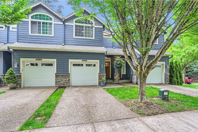 view of front facade with driveway, a garage, stone siding, and a shingled roof