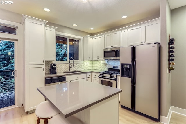 9480 SW 153rd Ave, Beaverton, OR 97007 - kitchen featuring appliances with stainless steel finishes, a sink, light wood-type flooring, backsplash, and white cabinets