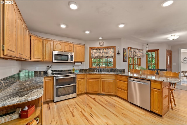 7654 N Bank Rd, Roseburg, OR 97470 - kitchen with appliances with stainless steel finishes, a peninsula, a kitchen breakfast bar, healthy amount of natural light, and recessed lighting