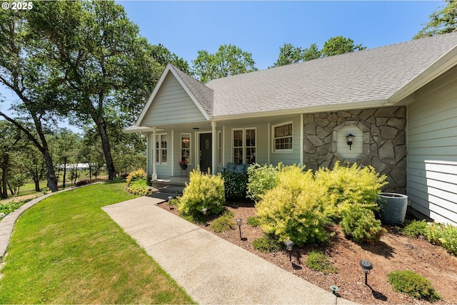 7654 N Bank Rd, Roseburg, OR 97470 - view of front of property featuring a porch, a shingled roof, a front lawn, stone siding, and central air condition unit