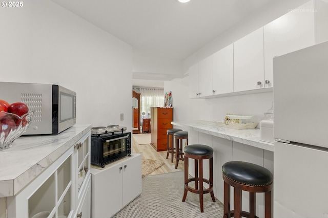2136 N Thorne St, Newberg, OR 97132 - kitchen featuring freestanding refrigerator, stainless steel microwave, a breakfast bar area, white cabinets, and light countertops