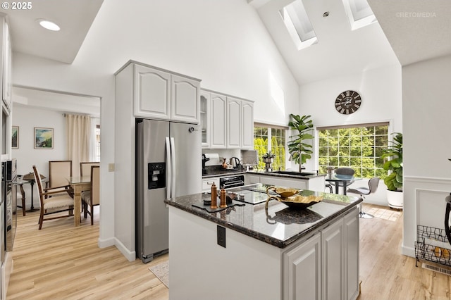 2136 N Thorne St, Newberg, OR 97132 - kitchen with stainless steel fridge with ice dispenser, high vaulted ceiling, a sink, a skylight, and a kitchen island