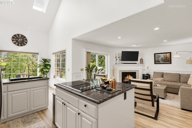 2136 N Thorne St, Newberg, OR 97132 - kitchen featuring a sink, a lit fireplace, light wood-type flooring, white cabinetry, and a kitchen island