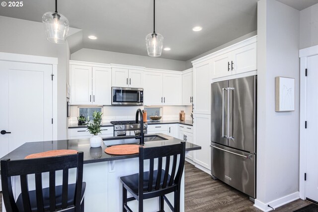 kitchen featuring dark countertops, high end appliances, white cabinets, dark wood-style floors, and recessed lighting