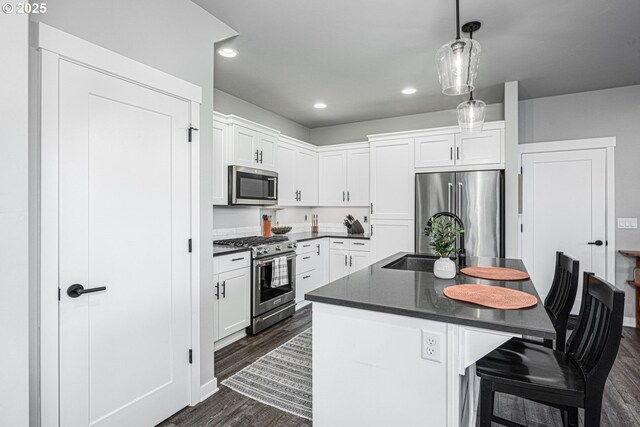 kitchen featuring a sink, a kitchen breakfast bar, stainless steel appliances, white cabinetry, and dark wood-type flooring
