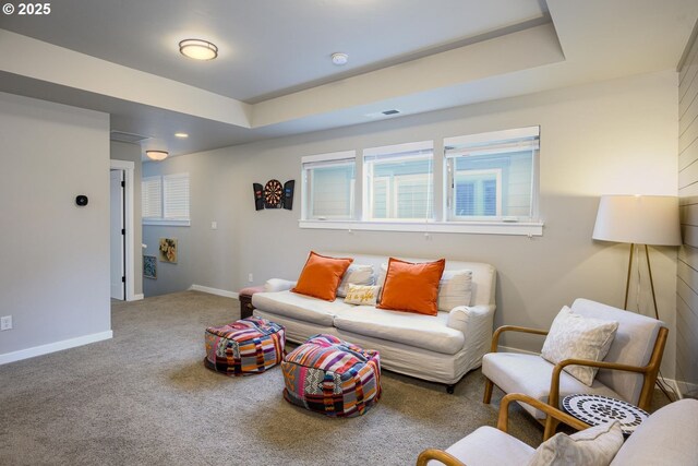 carpeted living area featuring a raised ceiling, baseboards, and visible vents