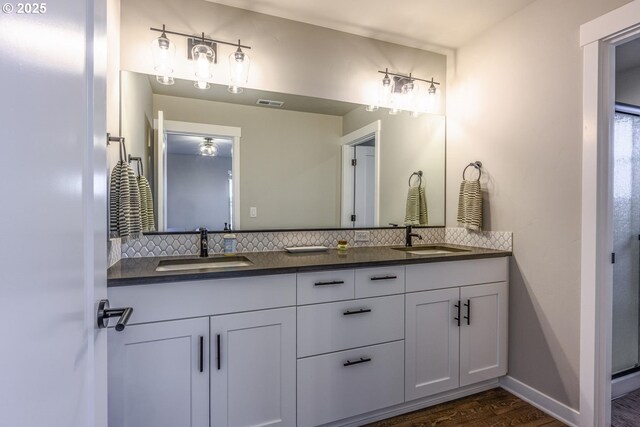 bathroom with backsplash, a sink, and wood finished floors