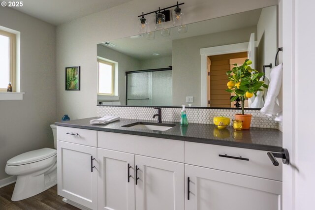bathroom with vanity, wood finished floors, toilet, and tasteful backsplash