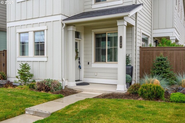 entrance to property featuring a lawn, fence, and board and batten siding