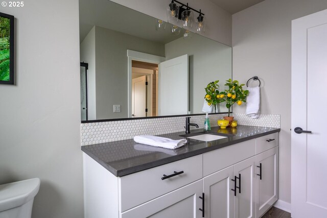 bathroom featuring vanity, decorative backsplash, and toilet