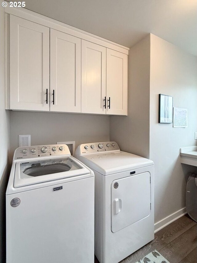 laundry room featuring separate washer and dryer, cabinet space, baseboards, and dark wood-style floors
