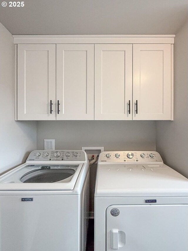 washroom with washer and clothes dryer and cabinet space