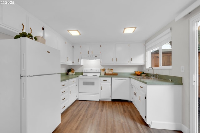 kitchen with white cabinets, a sink, wood finished floors, white appliances, and under cabinet range hood