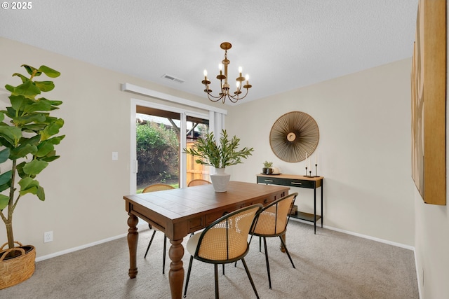 dining room featuring light colored carpet, a textured ceiling, baseboards, and an inviting chandelier