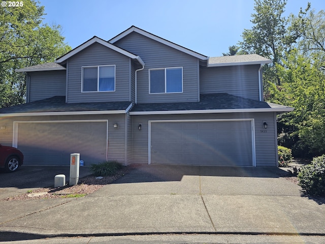traditional home with aphalt driveway, a garage, and a shingled roof