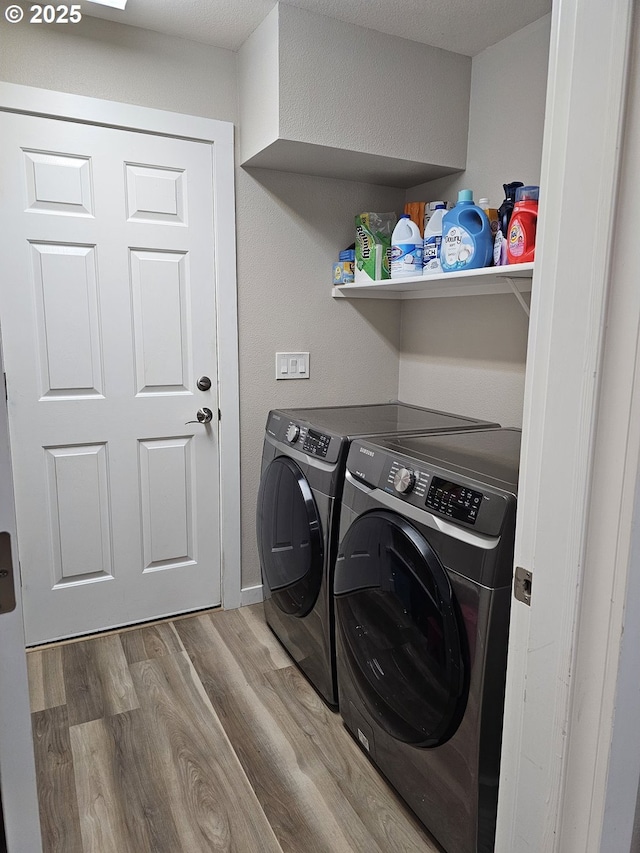 clothes washing area with washer and clothes dryer, laundry area, and wood finished floors
