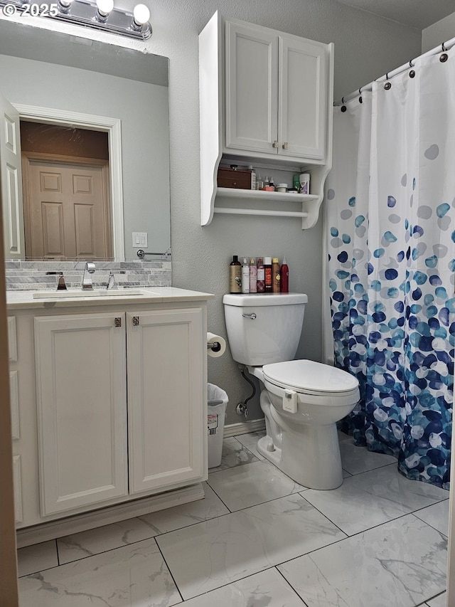 full bath with curtained shower, vanity, toilet, and marble finish floor