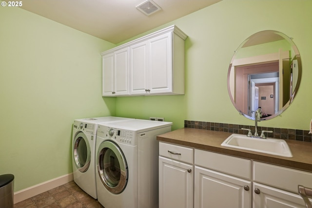 clothes washing area featuring sink, washer and clothes dryer, and cabinets