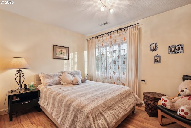 bedroom featuring light hardwood / wood-style floors and a textured ceiling