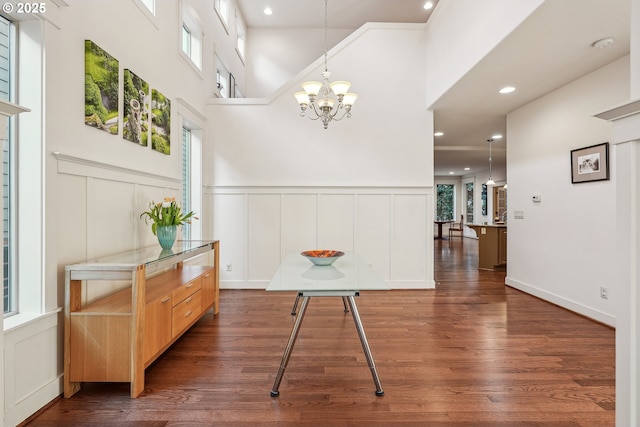 interior space with a notable chandelier, a towering ceiling, a wealth of natural light, and dark hardwood / wood-style floors