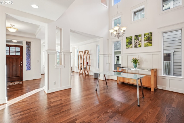 interior space featuring crown molding, dark wood-type flooring, a chandelier, and a towering ceiling