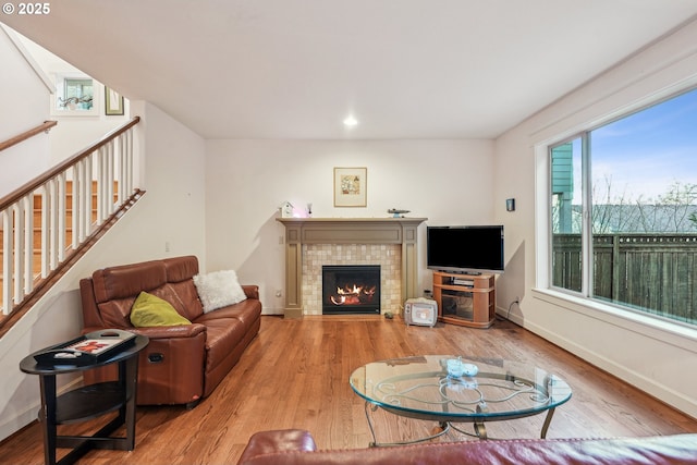 living room with wood-type flooring and a tile fireplace