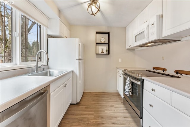 29650 SW Courtside Dr Unit 18, Wilsonville, OR 97070 - kitchen featuring stainless steel appliances, a sink, light countertops, light wood-type flooring, and white cabinetry