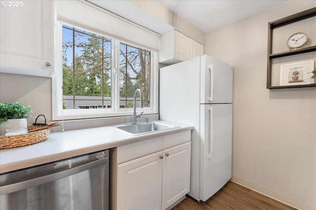 29650 SW Courtside Dr Unit 18, Wilsonville, OR 97070 - kitchen featuring dishwasher, a sink, freestanding refrigerator, wood finished floors, and white cabinetry