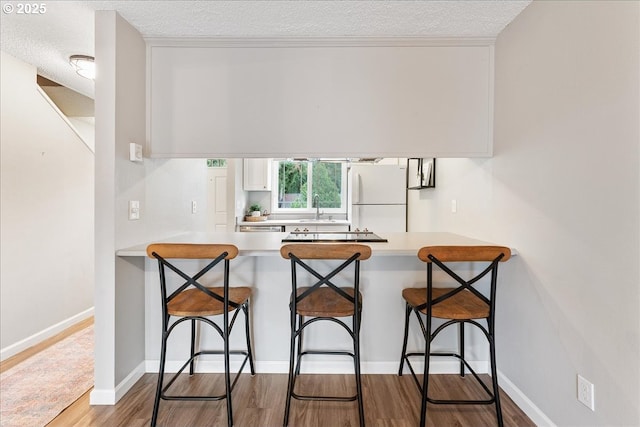 29650 SW Courtside Dr Unit 18, Wilsonville, OR 97070 - kitchen with freestanding refrigerator, a textured ceiling, a peninsula, light countertops, and wood finished floors