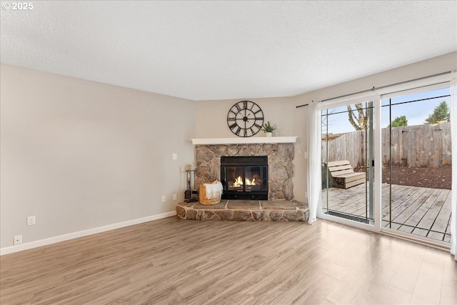 29650 SW Courtside Dr Unit 18, Wilsonville, OR 97070 - unfurnished living room featuring wood finished floors, a stone fireplace, baseboards, and a textured ceiling