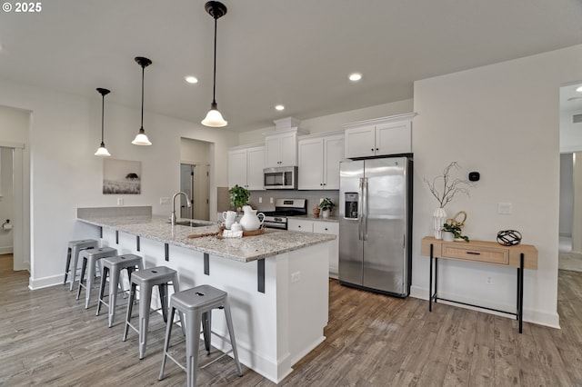 5316 SE Lone Oak St, Hillsboro, OR 97123 - kitchen with a breakfast bar, white cabinetry, stainless steel appliances, light wood finished floors, and a sink