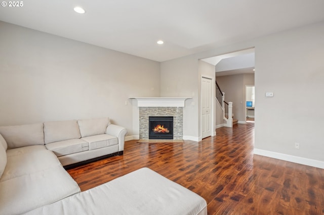 living room featuring a stone fireplace and dark wood-type flooring