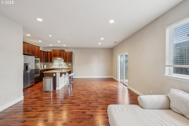 kitchen featuring stainless steel appliances, a breakfast bar, an island with sink, and a wealth of natural light